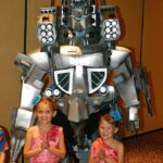 Paul Gavin’s Kiryu Mechagodzilla costume with two little girls as Mothra fairies standing in front